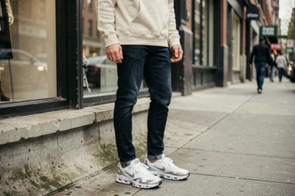 Jeune homme portant des Nike Shox Supreme blanches avec un jean indigo et un hoodie écru dans un cadre urbain